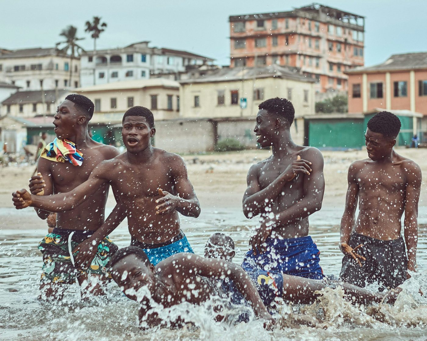 Young men laughing and splashing in the sea at a Ghanaian beach